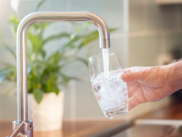 Wasser aus dem Hahn fließt in ein Glas